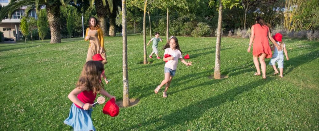 Kids and adults enjoy playing together in a lush, sunny park setting.